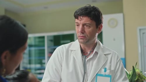 Male Pediatrician Talking to Mother of Sick Girl about Treatment