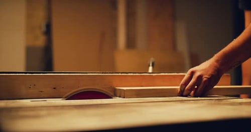 Male woodworker cuts lumber with table saw in professional studio lighting