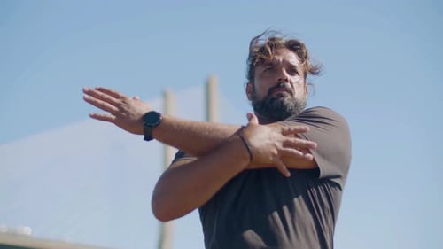 Man Stretching Arms Before Workout by the Bridge