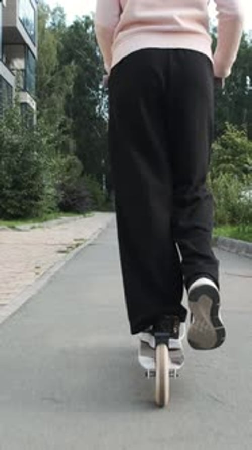 Une fille fait du scooter le long du chemin de la ville