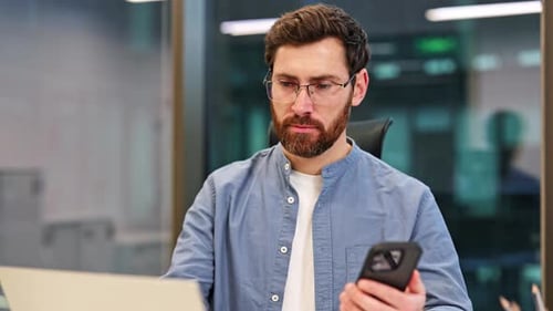 Businessman Working in Office Using Smartphone and Laptop