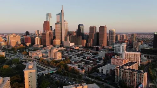 Slow aerial dolly forward shot of Philadelphia skyline during summer golden hour evening sunset