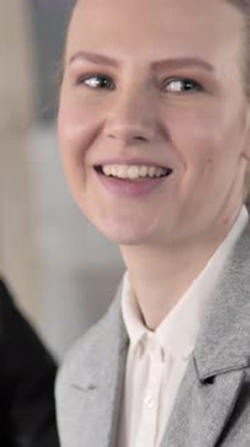 Woman in Blazer Smiling During an Office Meeting