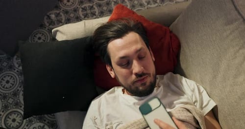 Un garçon endormi lève les yeux du canapé vers la pièce où il est allongé