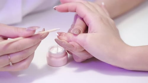 Close-up of a girl doing a manicure in a beauty salon. Nail care. Manicurist applies elastic nail po