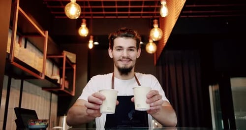 Smiling Barista Offers Coffee at Cafe Counter