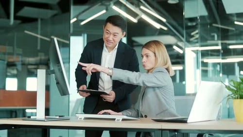 two business people consulting on a project looking at computer monitor screen sitting in the office