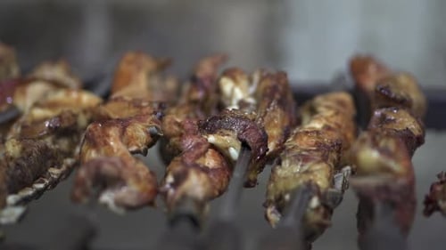 Meat on a skewer on the restaurant grill. Traditional Argentine barbecue. Closeup Slow motion.