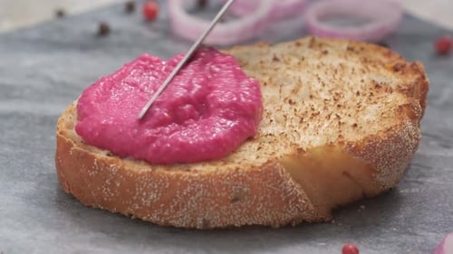 Spreading Pink Paste on a Slice of Bread