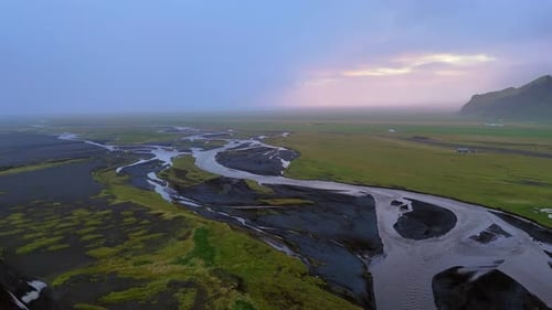 Glacial river braids travel to the horizon with mountain and storm, south Iceland.