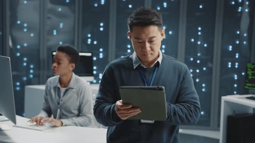 Portrait of Happy Asian IT Specialist Using Tablet Coworking in Successful Data Center Supercomputer