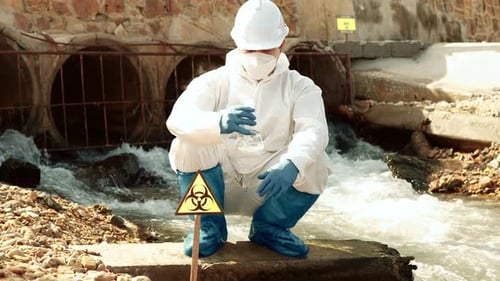 Scientist Examining Water Sample Near Polluted Stream