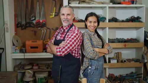Portrait of Caucasian carpenter or woodworker or charpentier man and Asian woman stand arm-crossed
