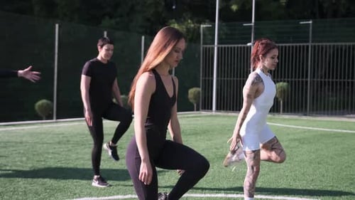 Women Perform Warm Up on Green Sports Field