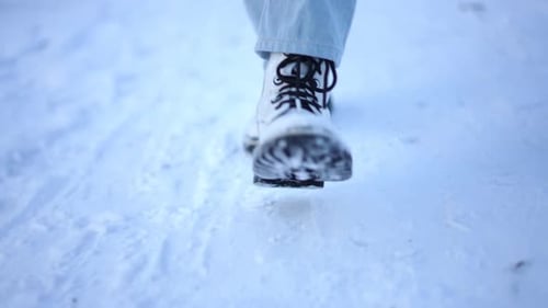 White Boots Walking Through Snow in Winter Landscape
