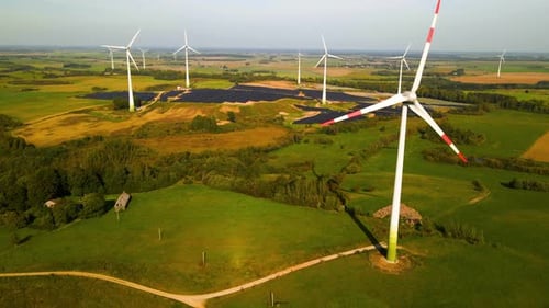 Aerial footage of wind turbines in a wind farm generating green electric energy on a wide green fiel