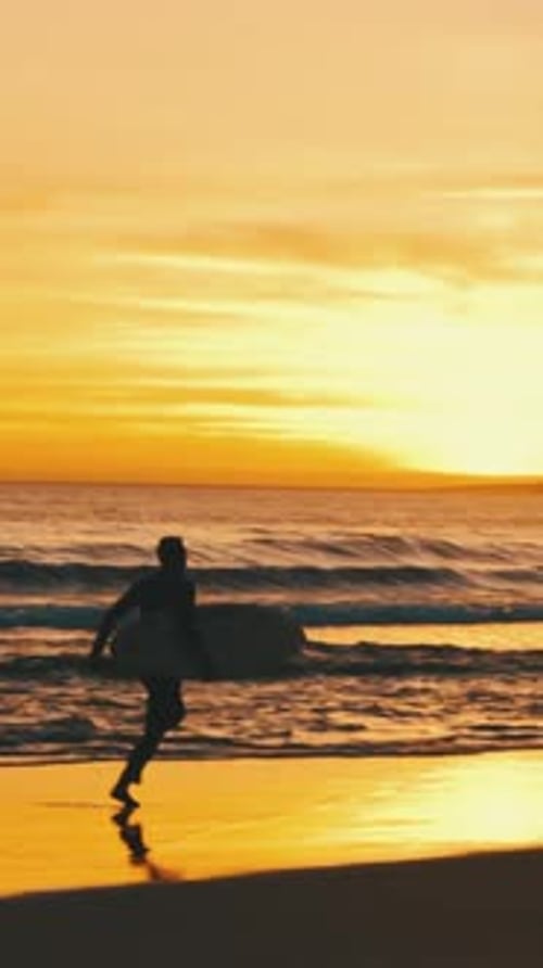 Man with Surfboard Running on Beach at Sunset