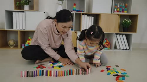 happy toddler girl and mother playing colorful wooden block toy or domino game together