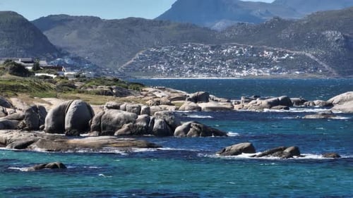 Idyllic turquoise bay with distant view of Cape Town hillside village - aerial