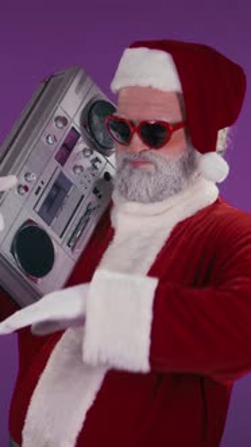 Vertical of Chilling Santa Dancing to Music from Jambox on Purple Background