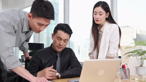 Office Workers Collaborate on Laptop in Bright Office