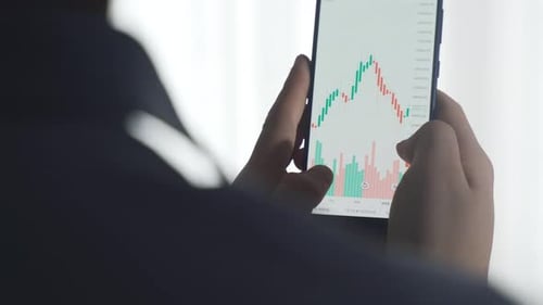 Vue rapprochée des graphiques du marché boursier et des cryptomonnaies depuis le téléphone.