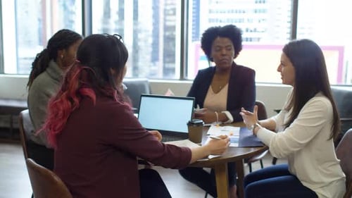 Businesswomen plan corporate strategy at table in highrise office