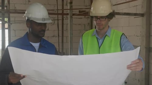 Engineers Reviewing Building Plans at Construction Site