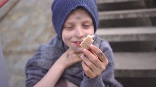 Homeless Boy Sits on Stairs in Bandoned Place Holding Bread in His Hand Migration Homeless Child