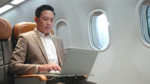Man Working on Laptop Aboard Airplane