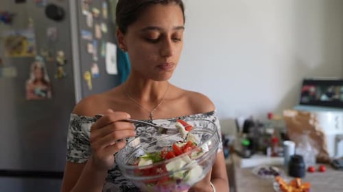 Young Woman Eating Salad in Bright Kitchen