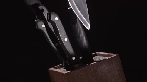 Set Of Kitchen Knives With Black Handle Placed On Wooden Knife Holder Isolated On Black Background -