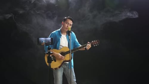 Man Singing and Playing Guitar With Microphone