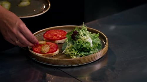 Close Up in a Professional Kitchen on Clean Metal Table a Woman Chef Collects a Salad with Fresh