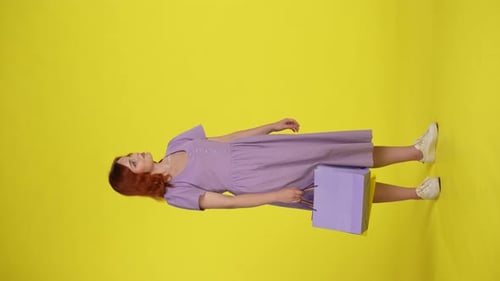 Woman Holding Shopping Bags Points Upward and Gives Thumbs Up