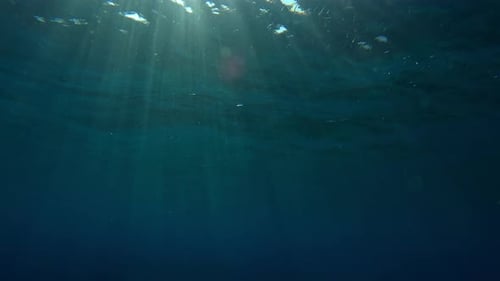 Bright sun rays under surface of water at sunset, underwater shot