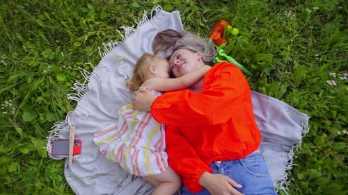Mother and Daughter Embracing on Blanket in Park