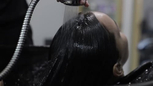 Stylist Washing Woman's Hair in Salon Close Up