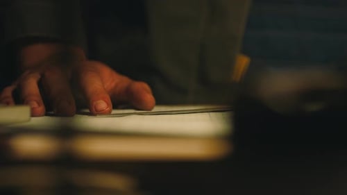 A male engineer works with drawings lying on the table, using a pencil