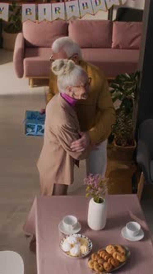 Seniors Celebrating Birthday with Hugs and Gifts at Home