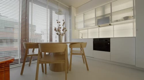Round wooden dining table with chairs in white kitchen apartment interior.