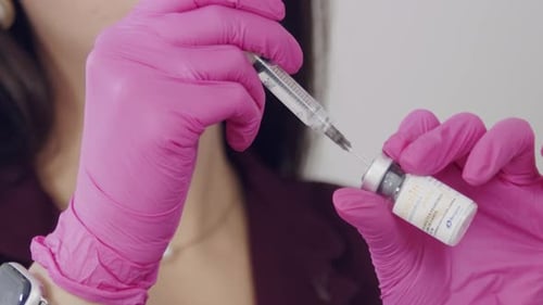 Medical Professional Extracts Serum From Vial with Needle