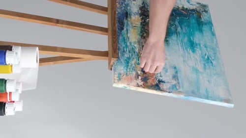 Der Künstler kreiert ein abstraktes Gemälde in einem Kunststudio auf grauem Hintergrund Vertikales Video