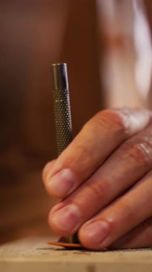Leathersmith Makes Hole in Leather with Metal Punch at Table