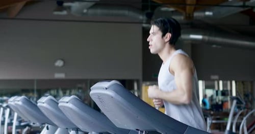 A guy in the gym to stay fit and have defined muscles or lose weight runs on the treadmill with a
