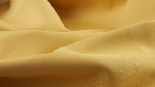 Top view of the soft folds of champagne brown cotton fabric rotated on the display case.