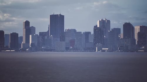 View of a Modern Skyline with Skyscrapers Along the Waterfront Under Cloudy Sky