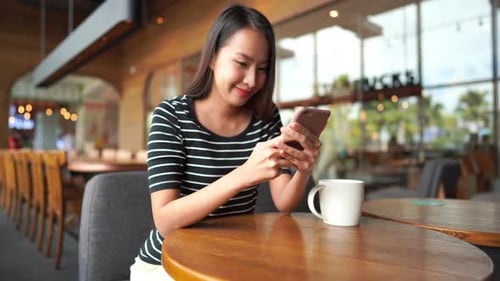 Woman Using Smartphone at Bright Cafe Table