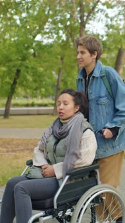Woman Pushing Friend in Wheelchair during Walk