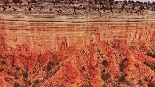 Large red rock formation in Spain with clear lines and plant life